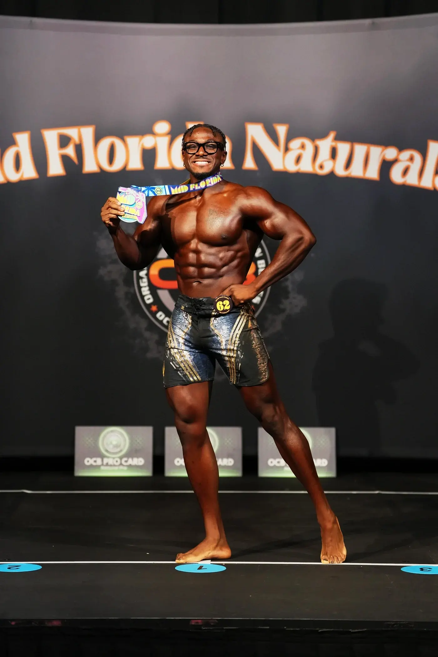 Robert smiling on the bodybuilding stage with his medal.