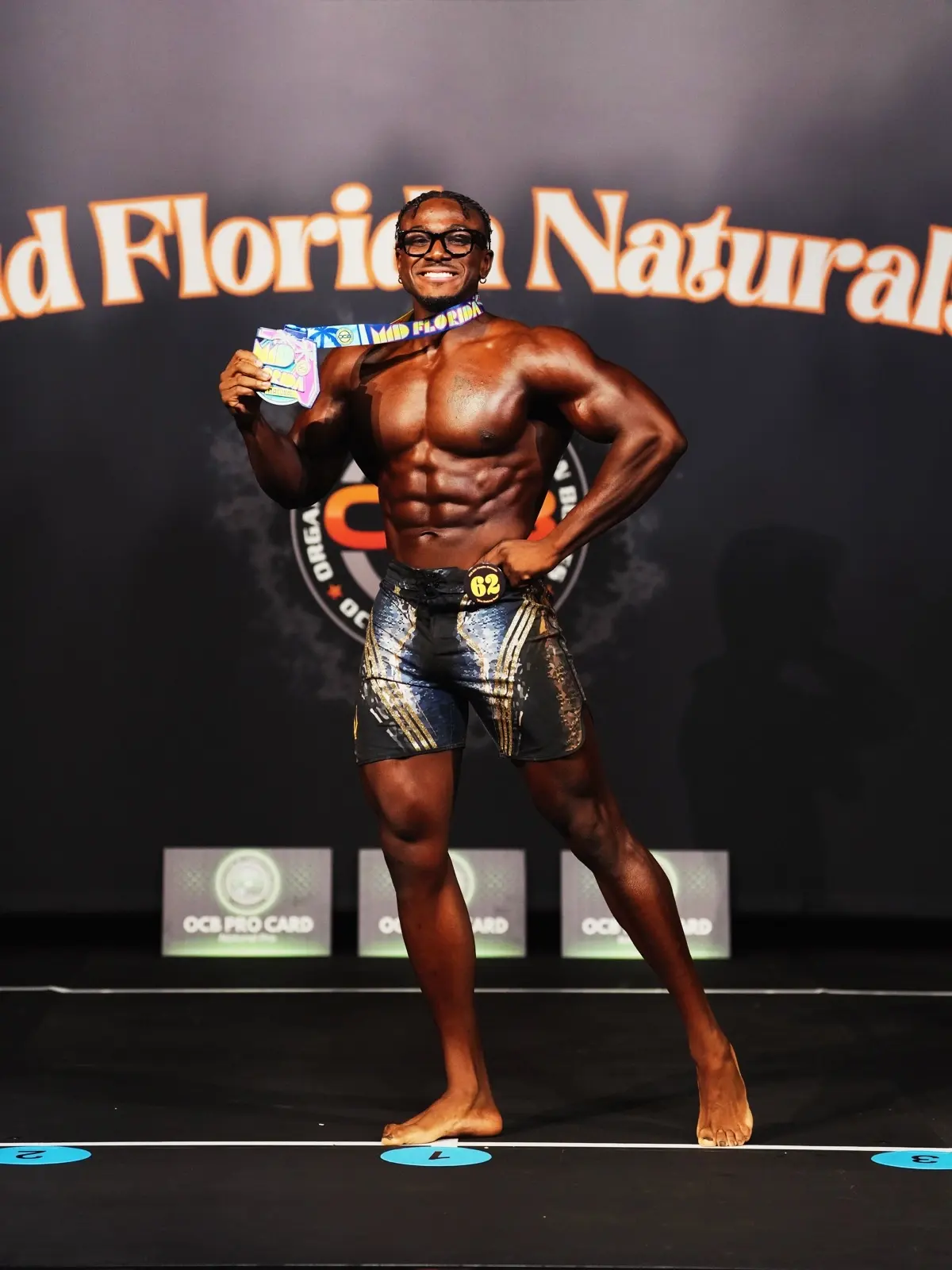 Robert smiling on the bodybuilding stage with his medal.